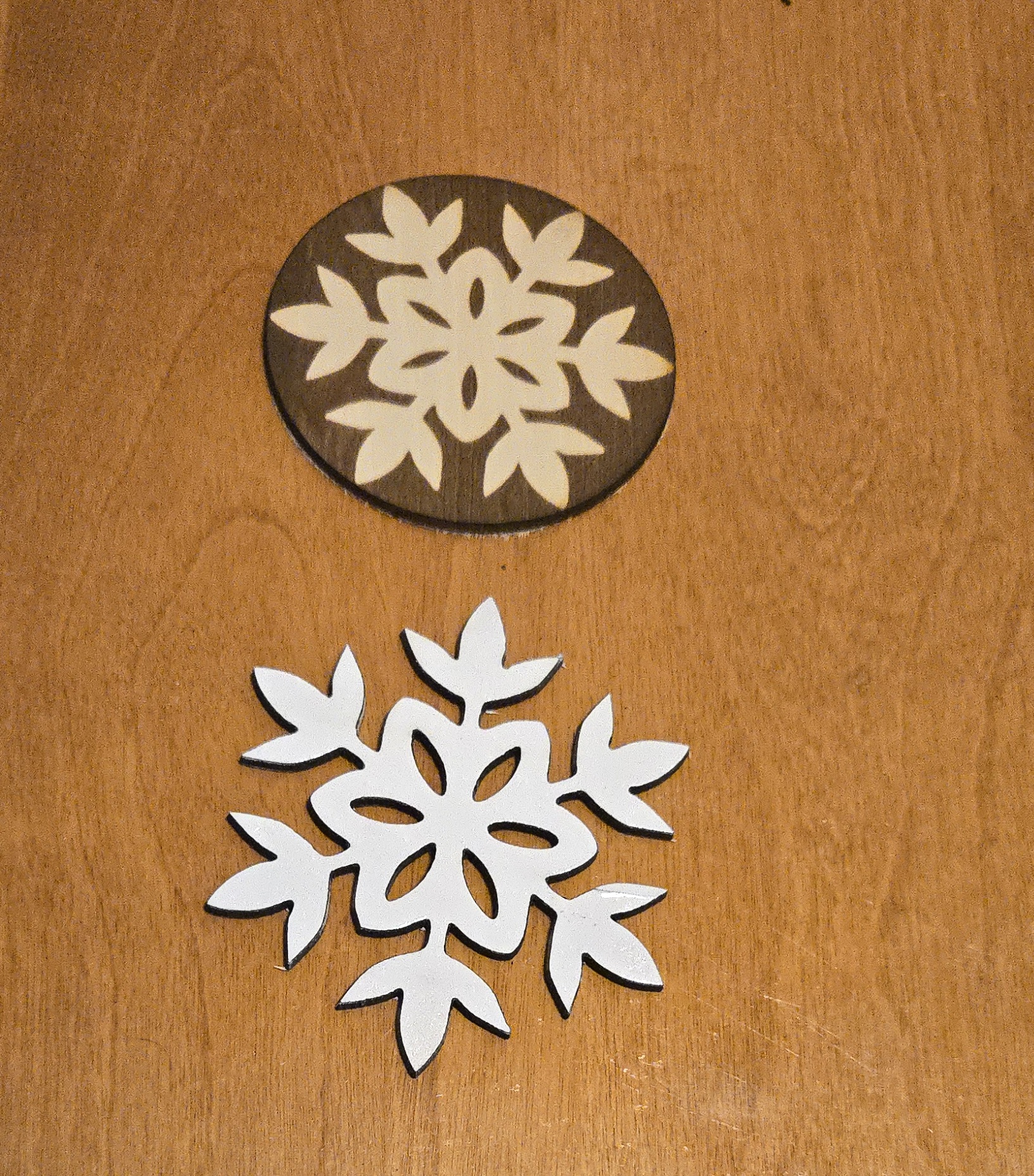 Wooden snowflake coaster and laser-cut white snowflake ornament by PetiteTrace