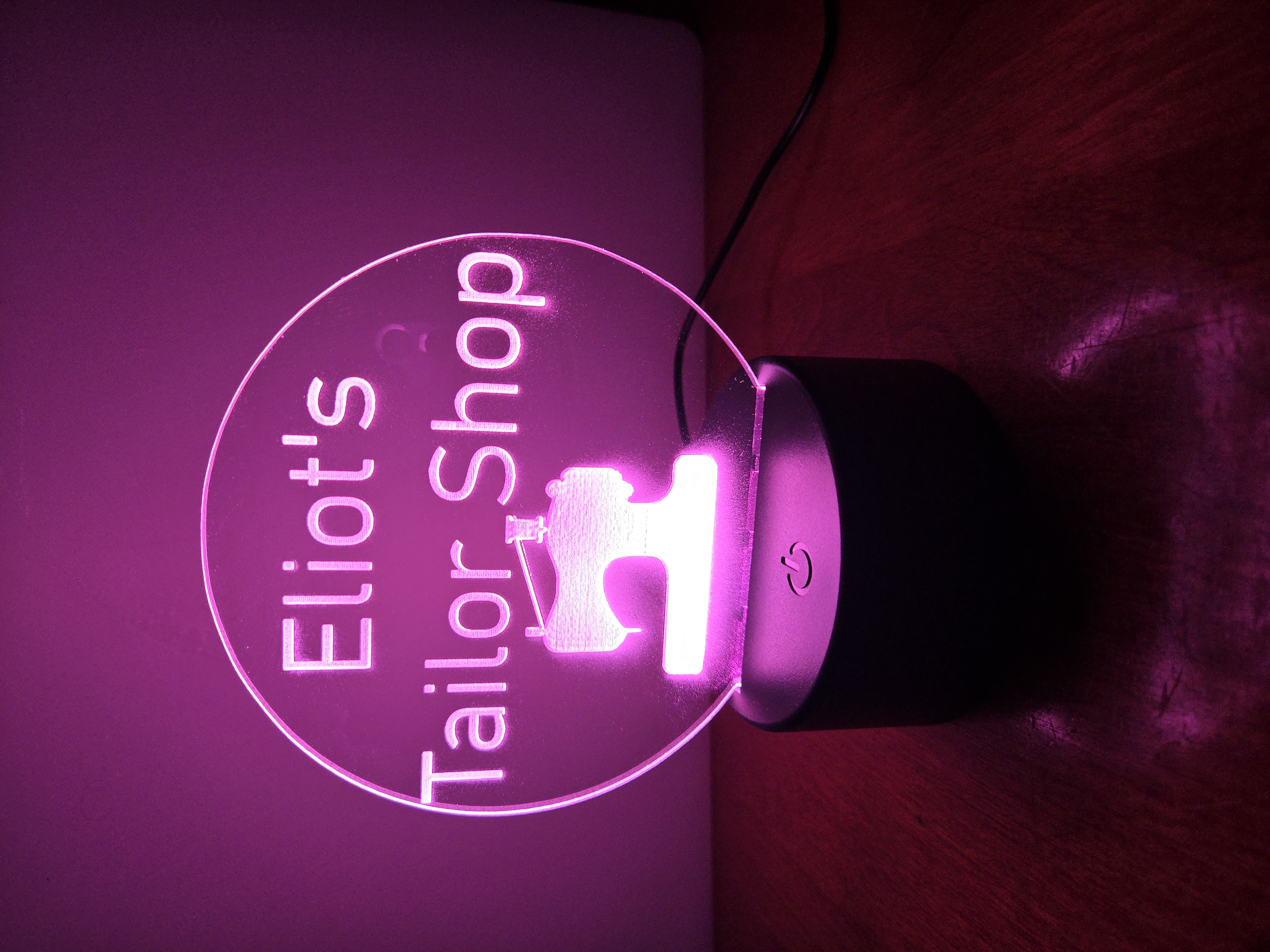 Custom LED acrylic night light sign for 'Eliot's Tailor Shop' with sewing machine icon, illuminated in pink by PetiteTrace