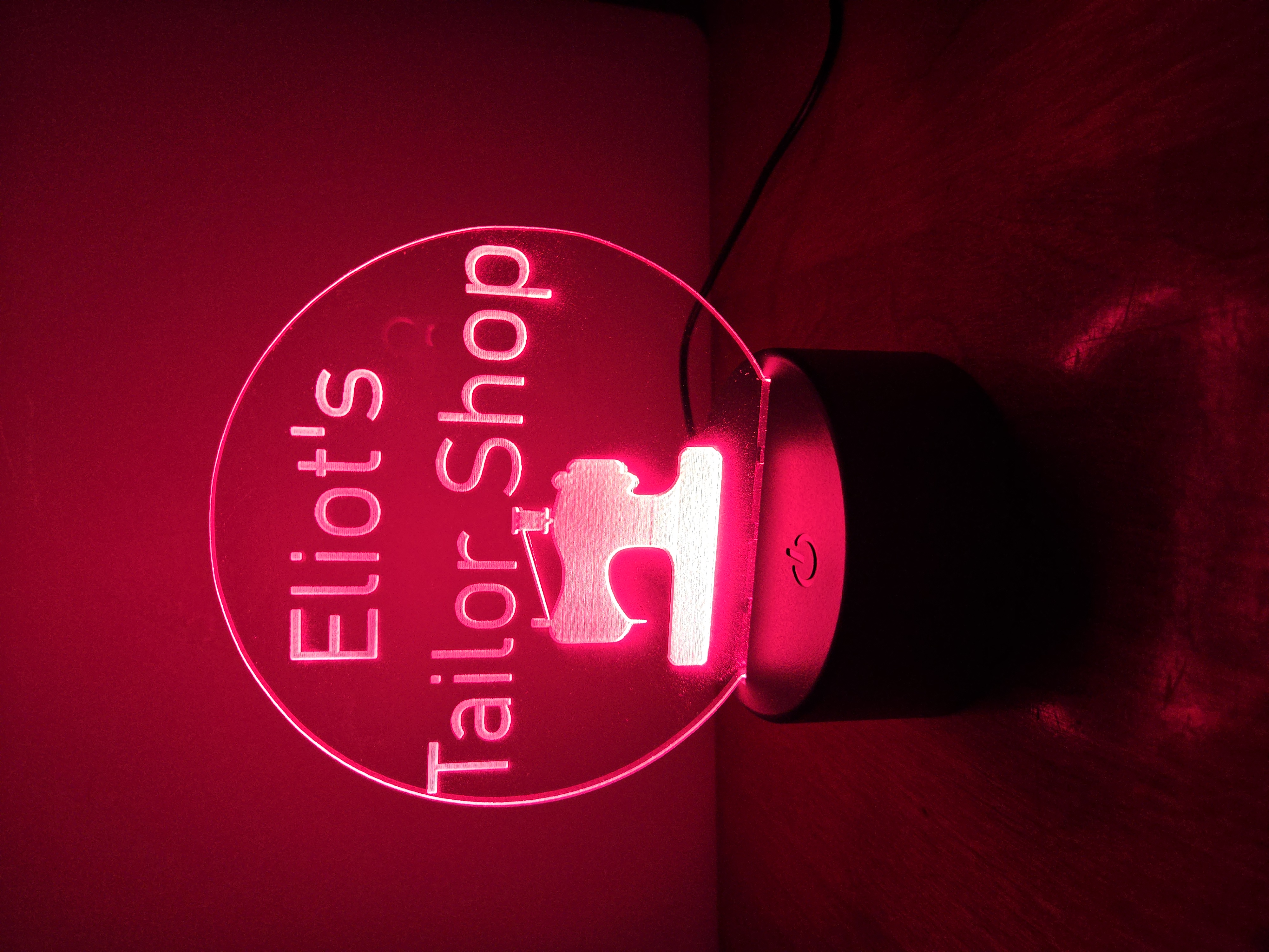 Custom LED acrylic night light sign for 'Eliot's Tailor Shop' with sewing machine icon, illuminated in red by PetiteTrace