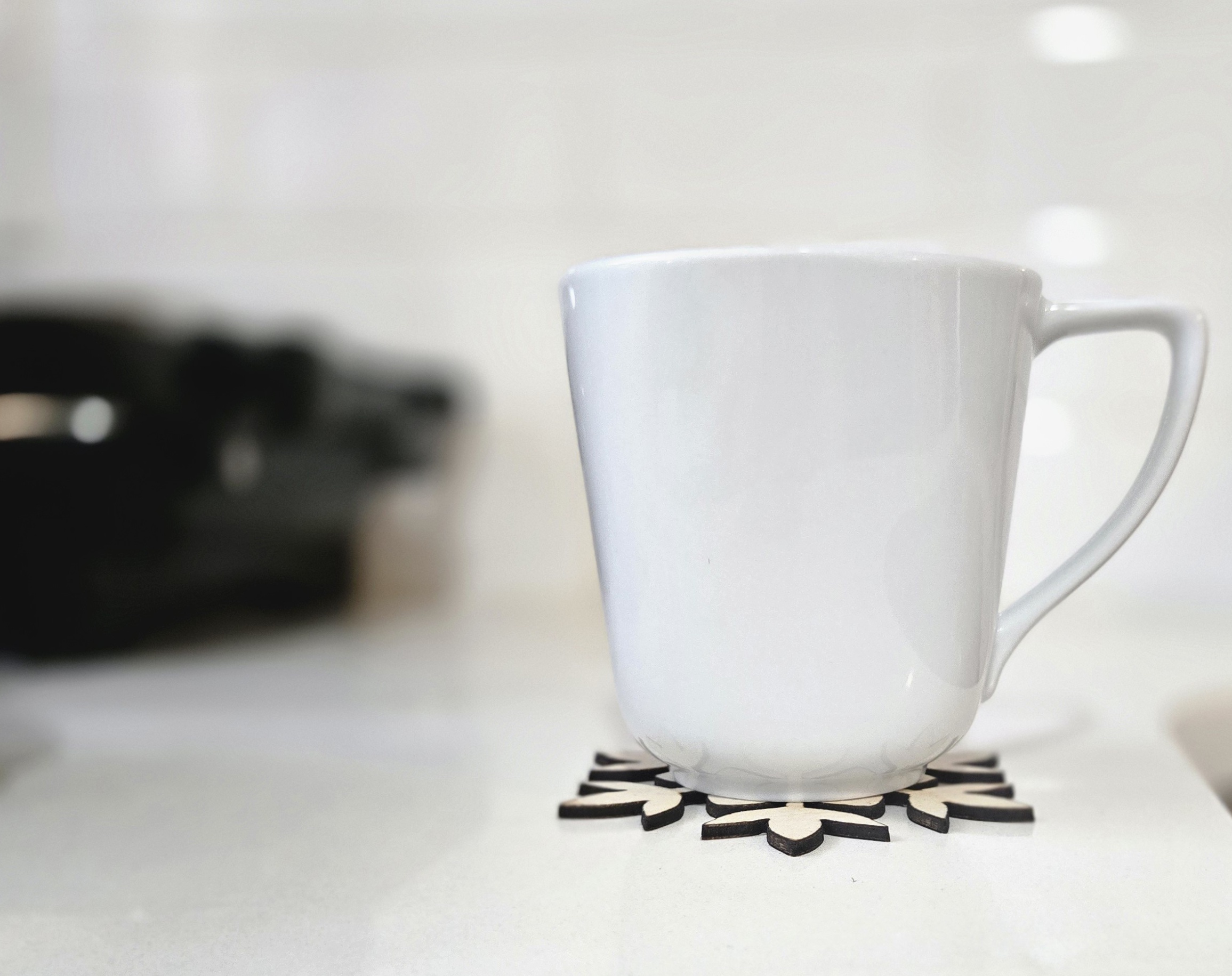 White mug resting on a laser-cut wooden snowflake coaster by PetiteTrace